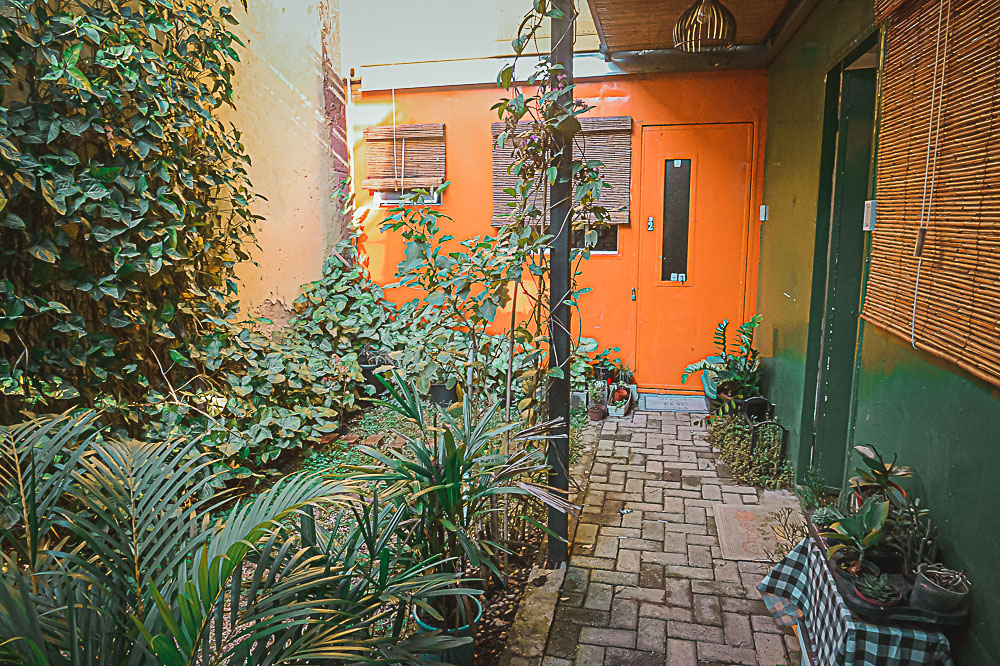Orange container door and lush garden path at The Voyager loft